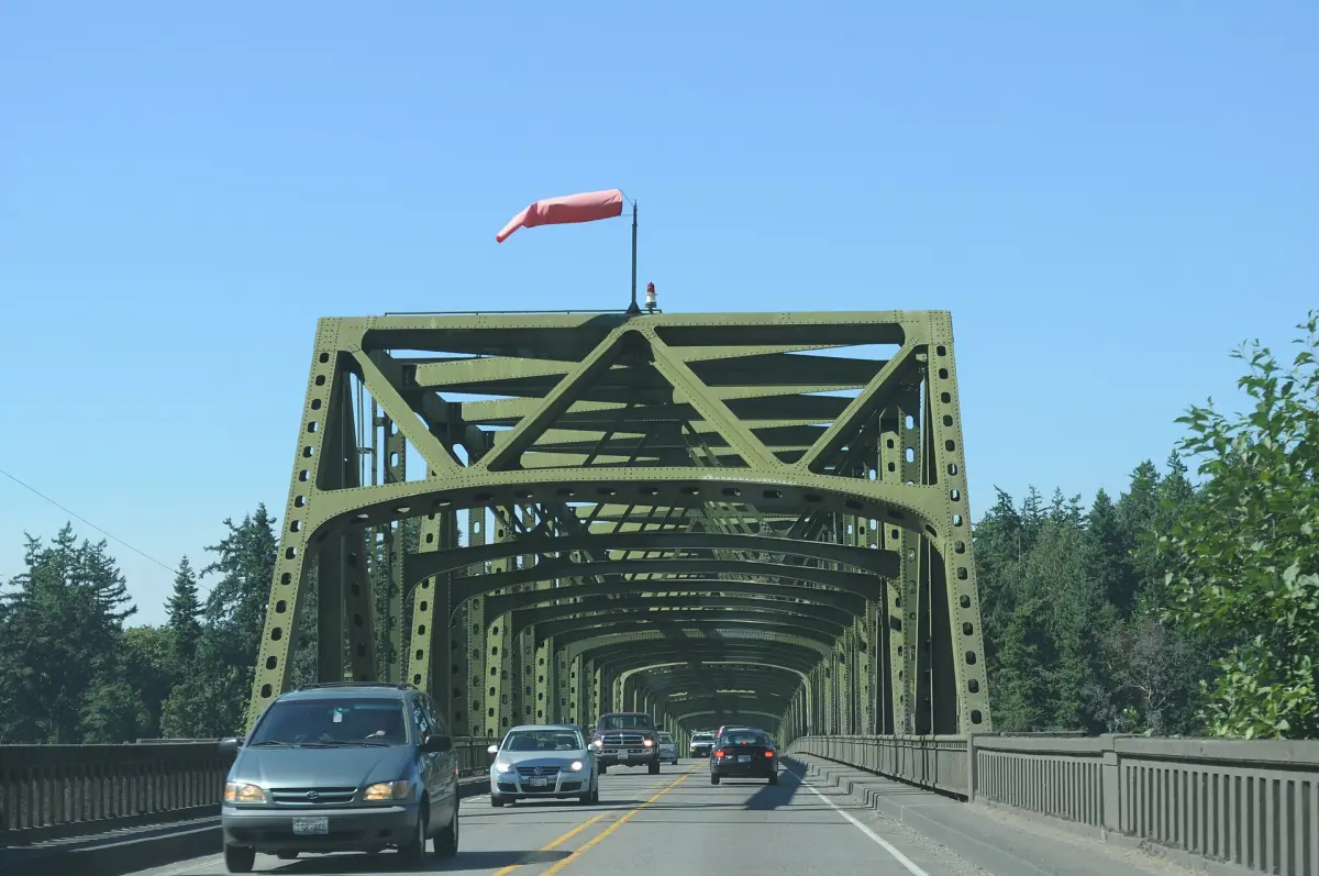 Steel truss bridge with cars crossing under a blue sky