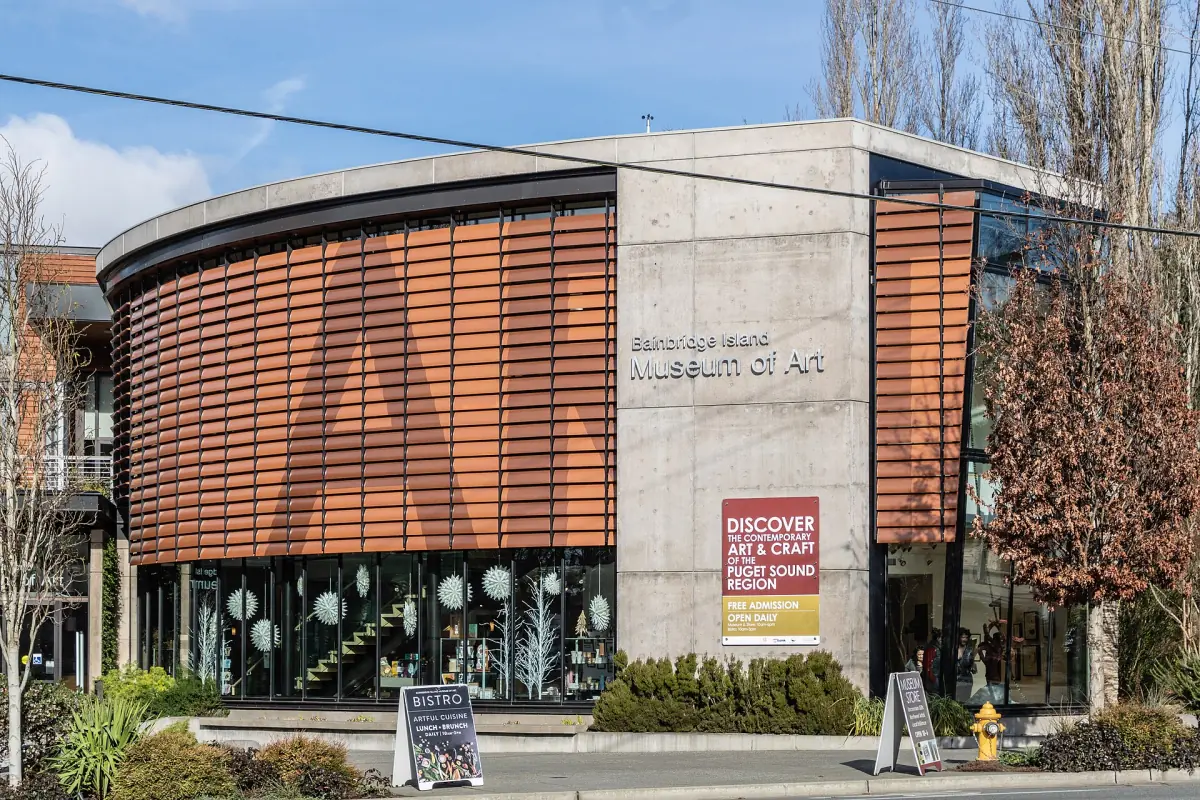 Curved museum building with wooden louvers and glass on a town street