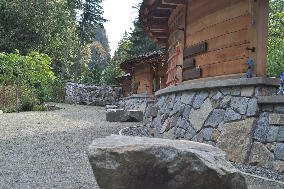 Gravel path along a stone wall and wooden structure at the memorial