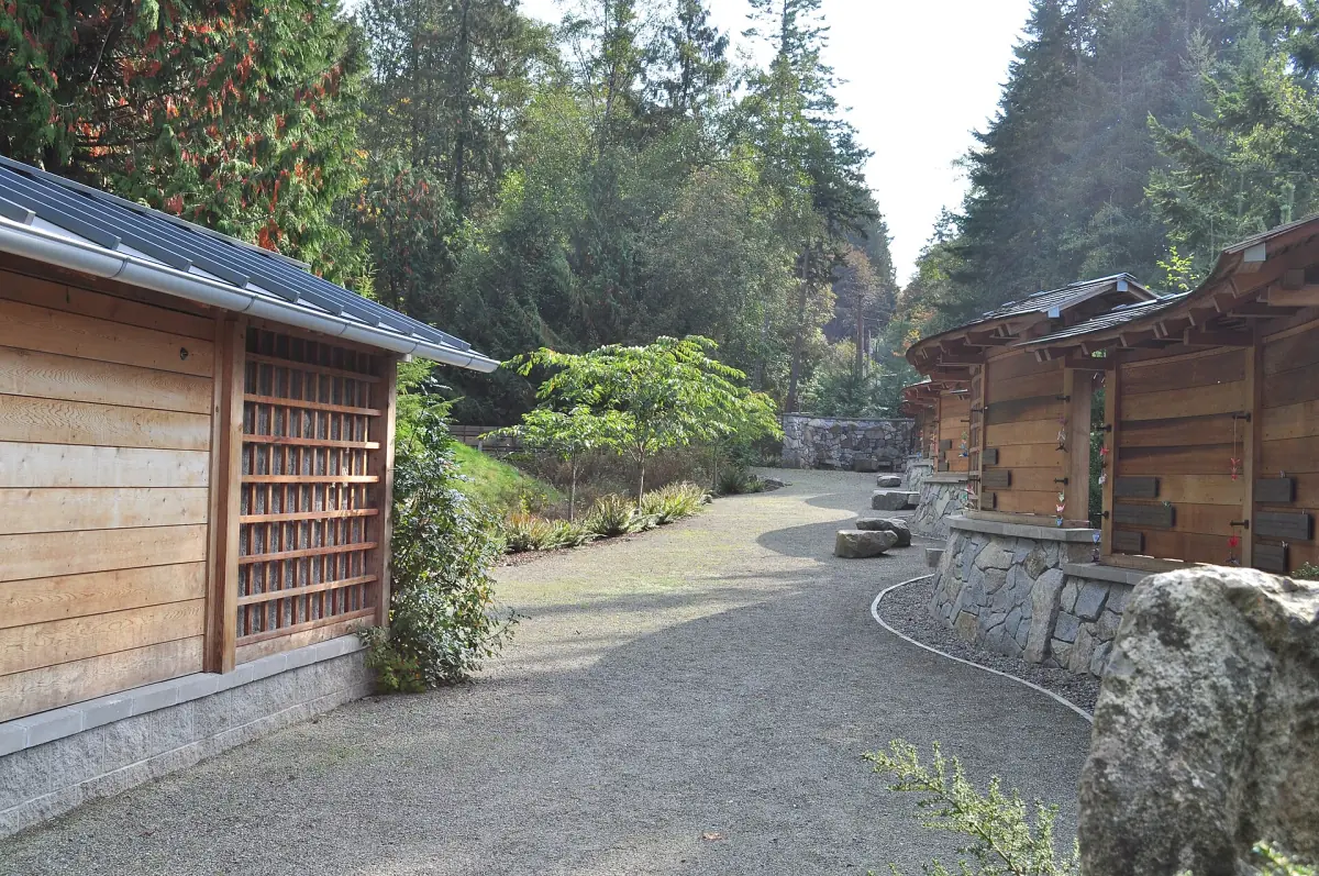 Long walkway beside a low stone wall and wooden panels in the forest