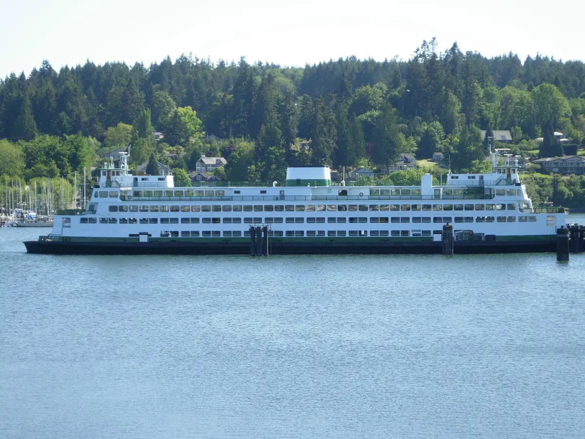 White car ferry crossing the water below forested hills